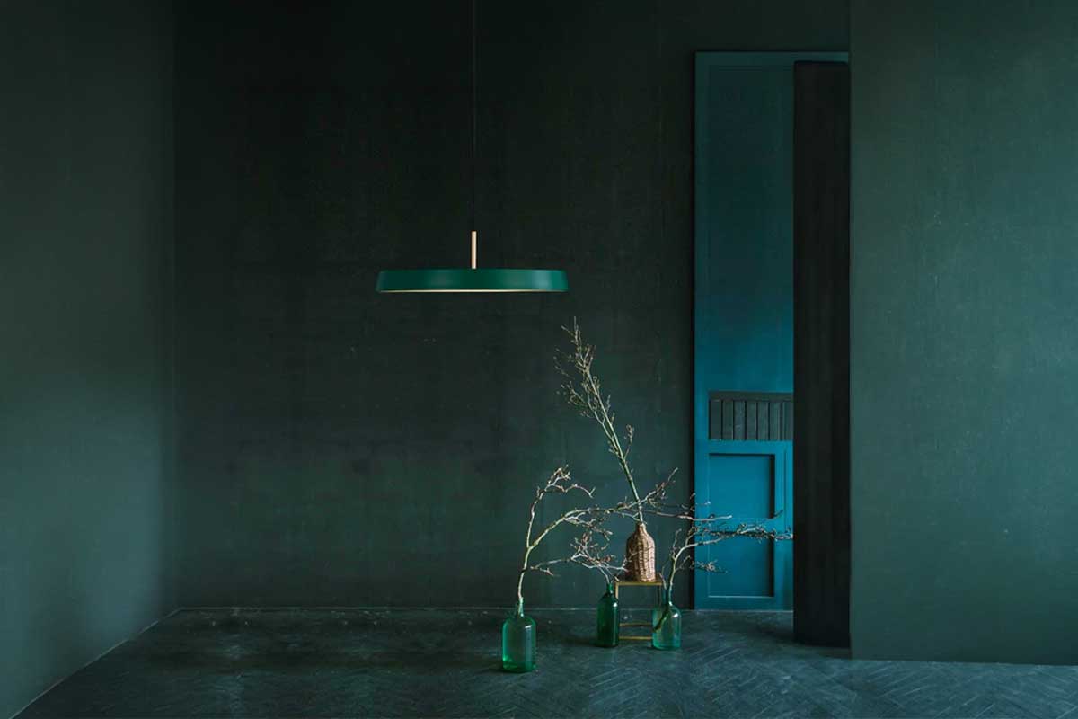 Minimalistický interiér s designovým závěsným svítidlem v tmavém prostoru